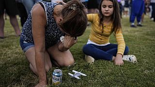 Brandy Rickaba and her daughter Emilie pray during a candlelight vigil for the slain students and teachers at Apalachee High School, Wednesday, Sept. 4, 2024, in Winder, Ga.