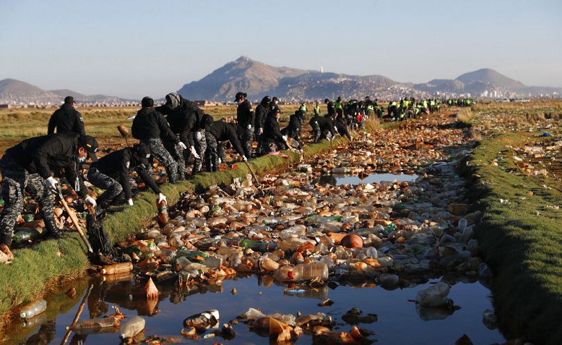 Police officers work to remove garbage from the polluted Tagaret River which flows into the Uru Uru Lake, near Oruro, Bolivia