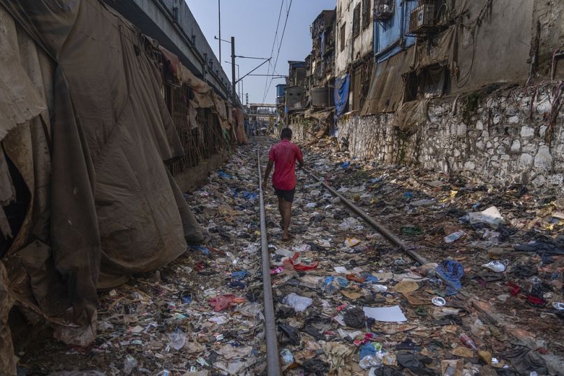 A man walks on a railway track littered with plastic and other waste materials in Mumbai, India