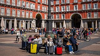 Tourists sit on a public bench in the Plaza Mayor square in downtown Madrid, Spain, Monday, April 29, 2024.