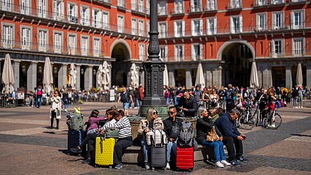 Turisti seduti su una panchina pubblica in Plaza Mayor, nel centro di Madrid (29 aprile 2024)