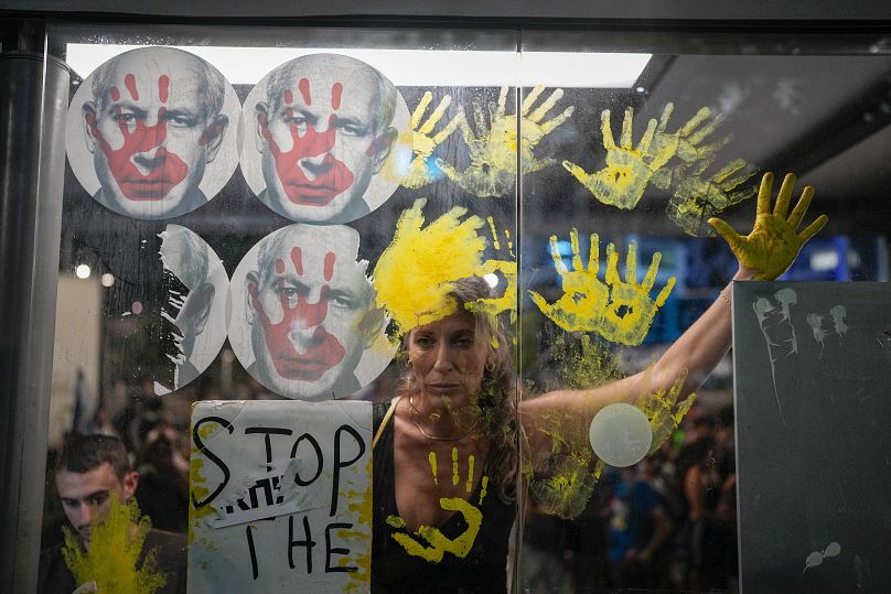 Demonstrators in Tel Aviv mark their hands on the window of a bus stop with photos of Israeli Prime Minister Benjamin Netanyahu, September 5, 2024