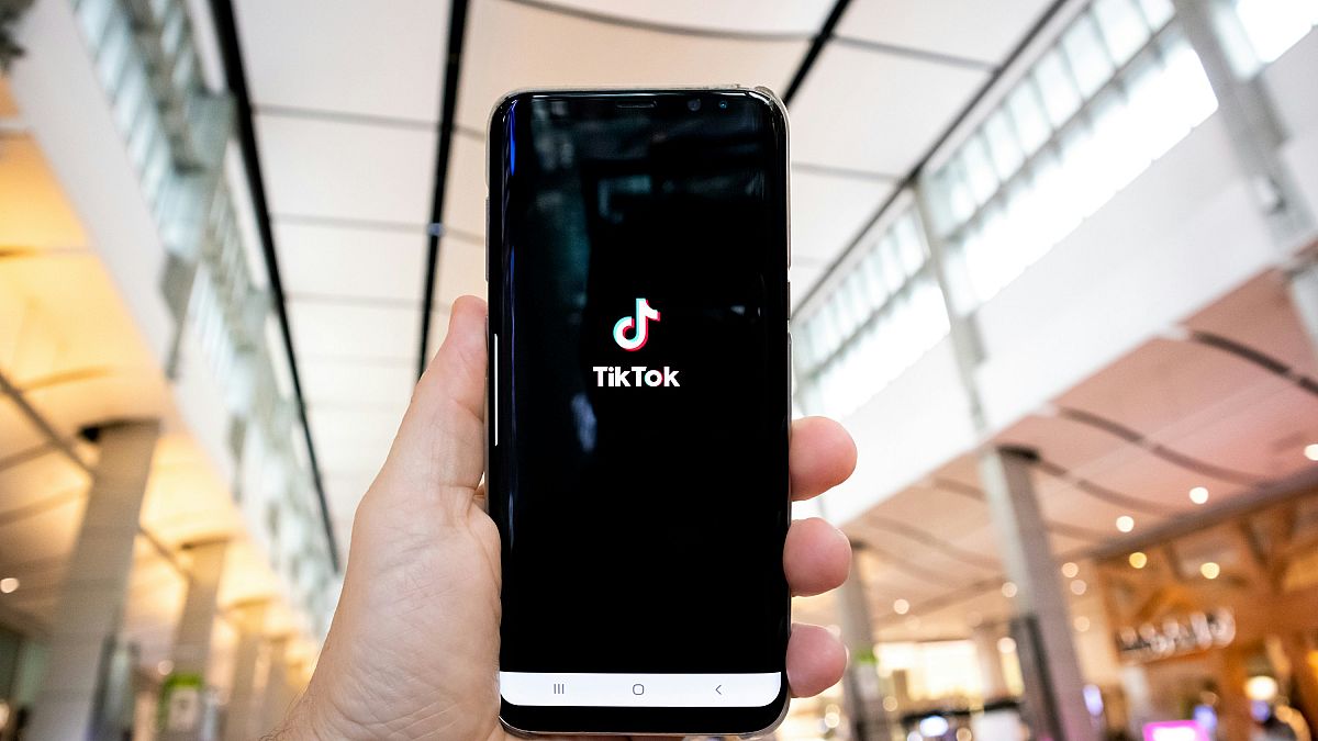 TikTok uygulama logosunu gösteren bir akıllı telefon tutan bir kişi