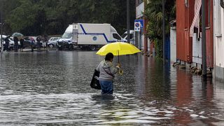 Uma mulher atravessa a água de uma inundação causada por fortes chuvas numa rua de Milão, a 5 de setembro de 2024