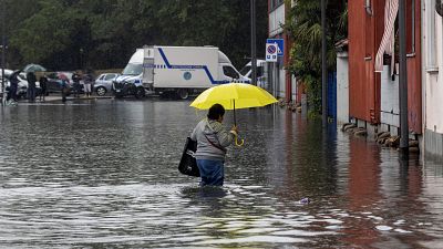 Uma mulher atravessa a água de uma inundação causada por fortes chuvas numa rua de Milão, a 5 de setembro de 2024