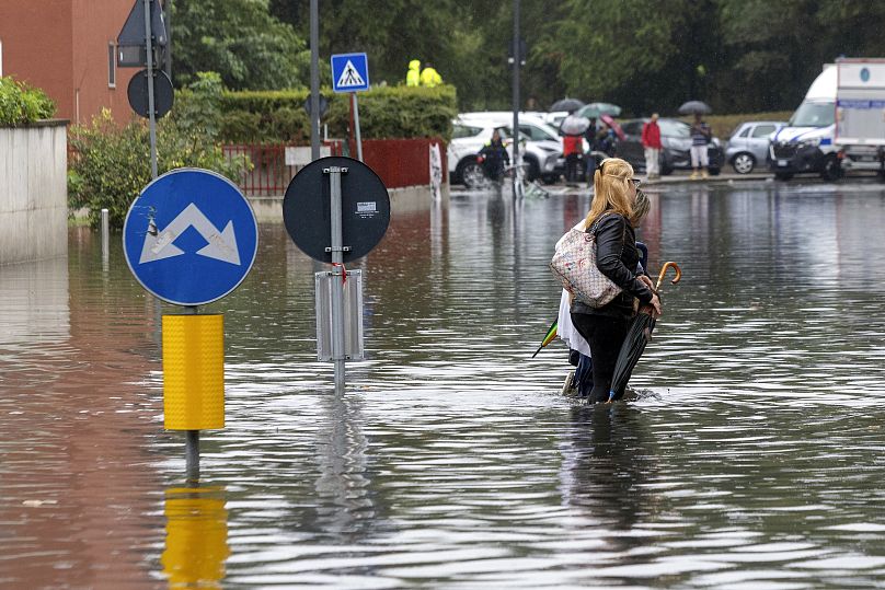 Due donne camminano nell'acqua causata dalle forti piogge in una strada di Milano, 5 settembre 2024