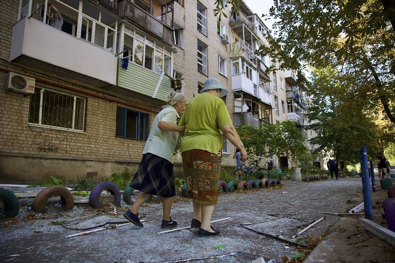 Mulheres locais caminham perto de um edifício residencial danificado por um ataque russo em Pavlohrad, 6 de setembro de 2024