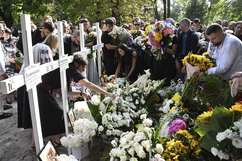 Des personnes déposent des fleurs sur les tombes des membres de la famille de Yaroslav Bazylevych dans un cimetière de la ville de Lviv, le 6 septembre 2024.