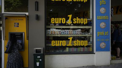 Une femme utilise un distributeur automatique de billets dans la ville principale de l'île de Rhodes, sur la mer Égée, le 10 mai 2022.