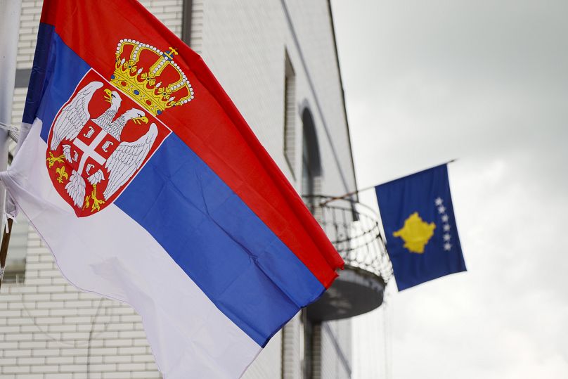 The Serbian flag, left, on a lamppost in front of a Kosovo flag on the city hall in the town of Zubin Potok, May 31, 2023