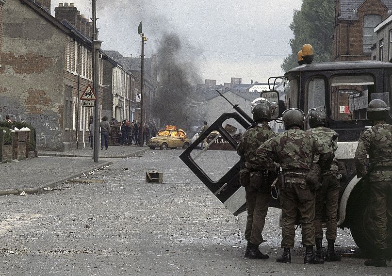 Des troupes britanniques, au premier plan, affrontent des manifestants dans un quartier à majorité catholique de Belfast pendant la période connue sous le nom de "Troubles"