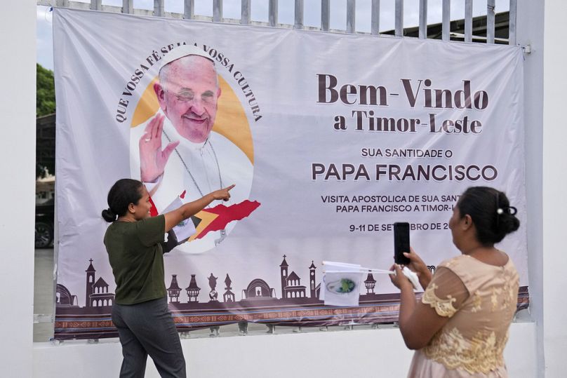 Uma mulher tira uma fotografia com uma faixa de boas-vindas ao Papa Francisco antes da sua visita a Timor-Leste, em Díli, domingo, 8 de setembro de 2024.