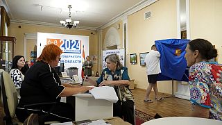 Une femme reçoit son bulletin de vote dans un bureau de vote pendant les trois jours de l'élection du gouverneur de la région de Koursk, à Koursk, Russie, dimanche 8 septembre