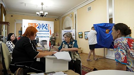 Une femme reçoit son bulletin de vote dans un bureau de vote pendant les trois jours de l'élection du gouverneur de la région de Koursk, à Koursk, Russie, dimanche 8 septembre