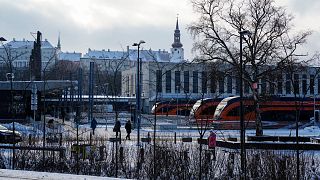 İnsanlar Baltık tren istasyonunda yürürken, solda Stenbock Evi ve üstte Aziz Mary Katedrali arka planda, Tallinn, Estonya, 22 Şubat 2023.