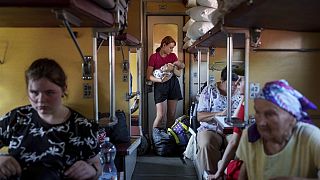 A girl calms her sister on an evacuation train in Pokrovsk, Donetsk region, Ukraine, Friday, Aug. 23, 2024. 