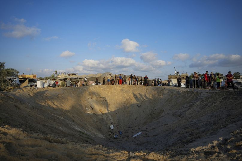 فلسطينيون ينظرون إلى الدمار بعد غارة جوية إسرائيلية على مخيم مزدحم يأوي فلسطينيين نزحوا بسبب الحرب في المواصي بقطاع غزة