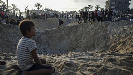 فلسطينيون يتفقدون الدمار بعد غارة جوية إسرائيلية استهدفت المنطقة الآمنة في مخيم النازحين، خان يونس، قطاع غزة