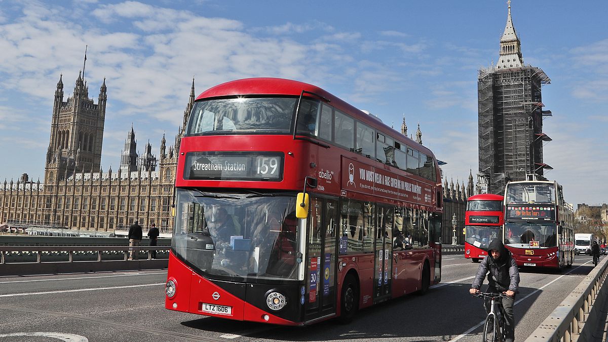 Otobüsler Londra'da, Parlamento Binası ve Elizabeth Kulesi'nin arka planında yer alan Westminster Köprüsü'nden geçiyor, 27 Nisan 2021