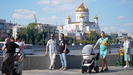 People walk on Krymskaya embankment of Moskva river with the Cathedral of Christ the Saviour in the background, in Moscow, 16 August 2024