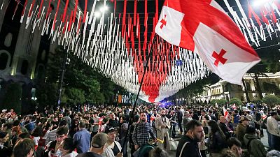 Manifestantes concentram-se junto ao edifício do Parlamento durante um protesto da oposição contra o projeto de lei sobre a influência estrangeira, em Tbilissi.