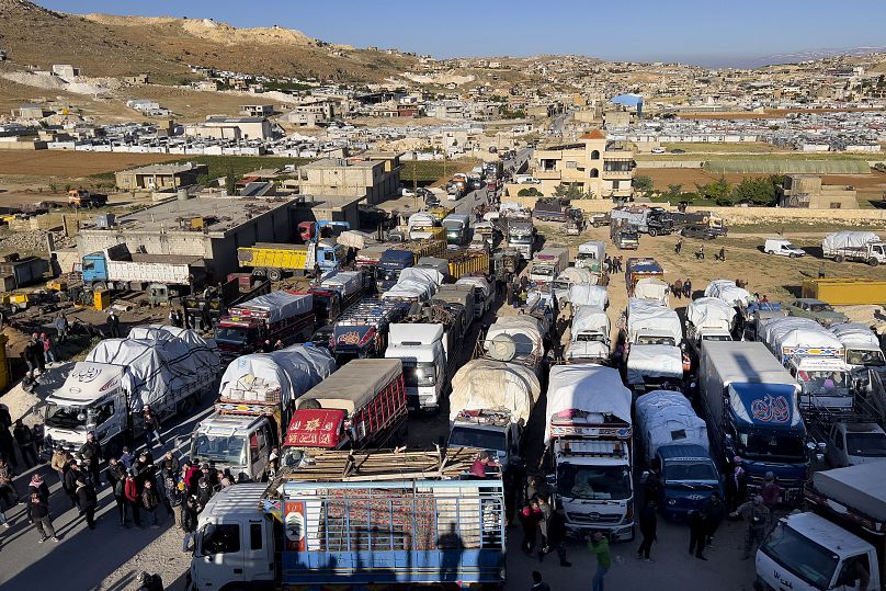 Syrian refugees near trucks with their belongings, as they prepare to go back to Syria as a part of a voluntary return, in the Lebanese border town of Arsal, May 2024