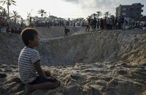 Palestinians look at the destruction after an Israeli airstrike on a crowded tent camp in Muwasi.