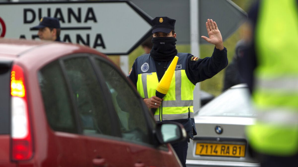 Um agente da polícia pára um veículo num posto de controlo perto da fronteira entre Espanha e França em La Jonquera, Girona, Espanha, sábado, 28 de abril de 2012.