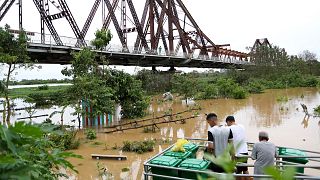 People watch the flooded Red river next to iconic Long Bien bridge, following Typhoon Yagi in Hanoi, Vietnam.