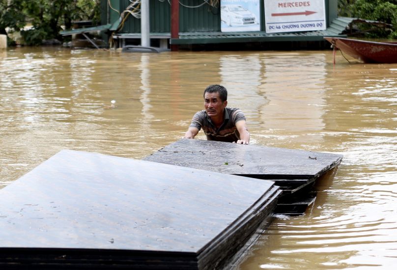 A man pushes a stack of plyboards in flood following Typhoon Yagi in Hanoi, Vietnam.