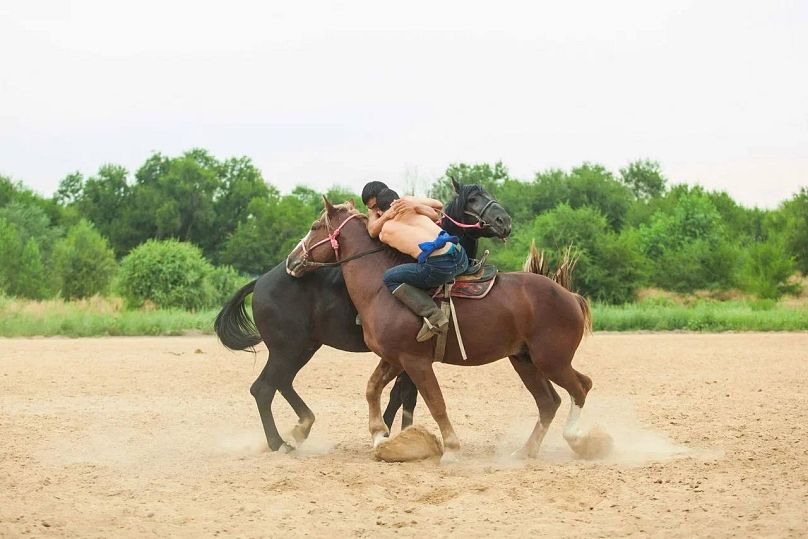 Audaryspaq sees two competitotrs, each on horseback, wrestle to pull the other off their horse.