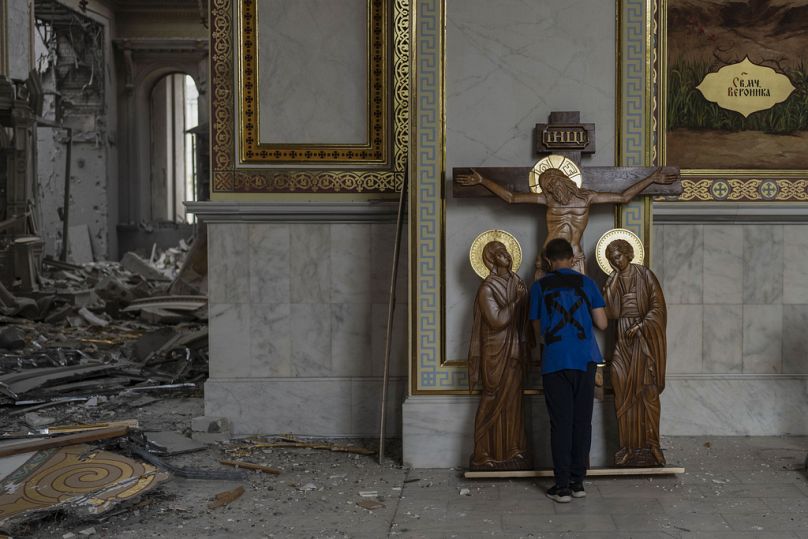 A boy kisses the statue of Jesus while helping clean up inside the Odesa Transfiguration Cathedral after the church was heavily damaged in Russian missile attacks in Odesa, Uk