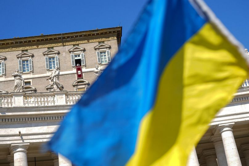 A person waves a Ukrainian flag as Pope Francis recites the Angelus noon prayer from the window of his studio overlooking St.Peter's Square, at the Vatican