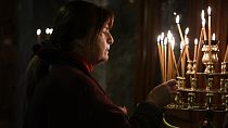 Una mujer enciende una vela durante una Divina Liturgia de Navidad, en la Iglesia Ortodoxa Griega de Panagia (Virgen María) Kapnikarea en Atenas, 25/12/2023