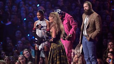 Taylor Swift, ao centro, e Post Malone, à direita, aceitam o prémio de melhor colaboração por "Fortnight" durante os MTV Video Music Awards na quarta-feira, 11 de setembro de 2024