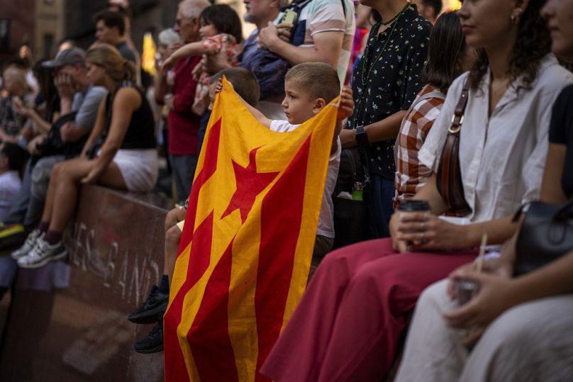 Tom, 4, hält eine Entelada (Unabhängigkeitsfahne), während er sich eine Aufführung eines menschlichen Turms während des katalanischen Nationalfeiertags, der Diada, ansieht