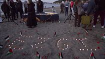 O nome da ativista de 26 anos de Seattle, morta recentemente na Cisjordânia, é soletrado em velas na areia durante uma vigília na praia de Alki, quarta-feira, 13 setembro 2024