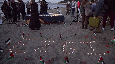 O nome da ativista de 26 anos de Seattle, morta recentemente na Cisjordânia, é soletrado em velas na areia durante uma vigília na praia de Alki, quarta-feira, 13 setembro 2024