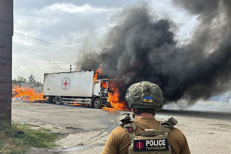 A police officer looks at a burning Red Cross vehicle that was destroyed in a Russian strike in the Donetsk region, September 12, 2024