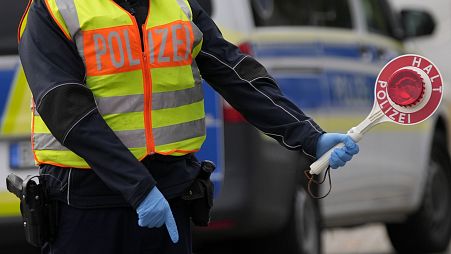 A German federal police officer stops cars and trucks at a border crossing point between Germany and Czech Republic in Furth am Wald, Germany.