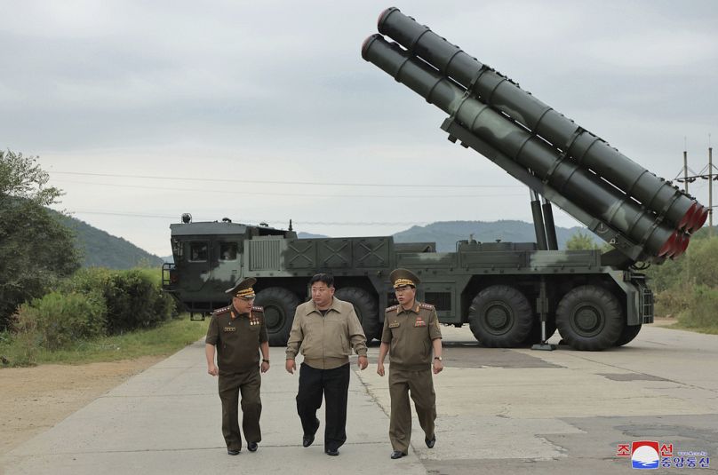 Kim Jong Un, en el centro, delante de lo que define como su nuevo vehículo de lanzamiento de cohetes múltiples de 600 mm. en un lugar no revelado en Corea del Norte.