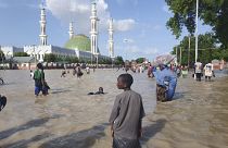 People walk through floodwaters following a dam collapse in Maiduguri, Nigeria, Tuesday Sept 10, 2024.