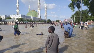 People walk through floodwaters following a dam collapse in Maiduguri, Nigeria, Tuesday Sept 10, 2024.