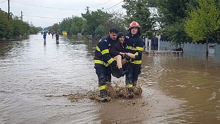 In this photo released by the Romanian Emergency Services Galati (ISU Galati), a rescuer carries a woman in Pechea, Romania, Saturday, Sept. 14, 2024