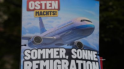 An AfD election campaign posters showing the slogan "summer, sun, remigration," and the photo of a plane dubbed "deportation airline" is displayed in Erfurt, Germany, Wednesda