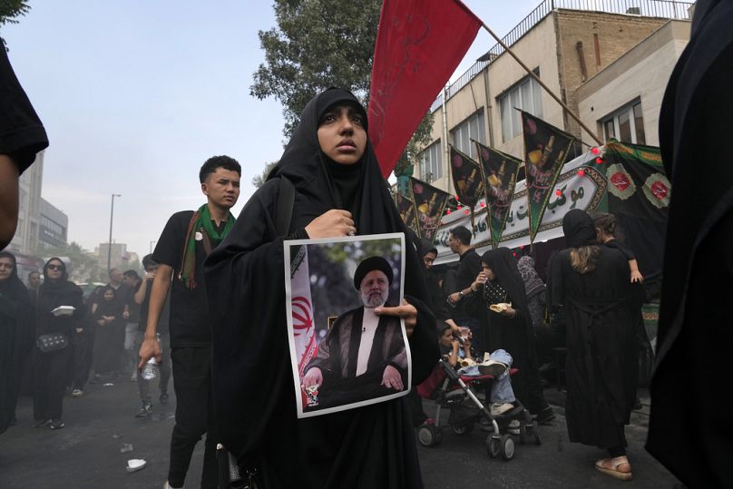 A mourner carries a poster of the late Iranian President Ebrahim in Tehran, Iran, Sunday, Aug. 25, 2024