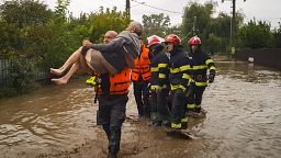 A rescuer carries an old man in Pechea, Romania, Saturday, Sept. 14, 2024 after torrential rainstorms left scores of people stranded in flooded areas. 