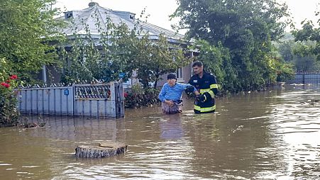 Egy mentő segít egy nőnek elhagyni a házát a romániai Pecheában