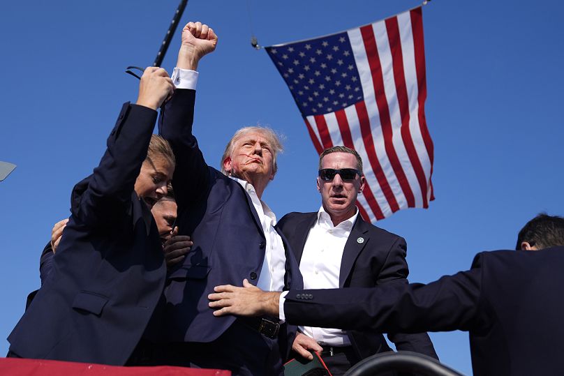 Former President Donald Trump is surrounded by Secret Service agents following an assassination attempt at a campaign rally in Butler, July 13, 2024