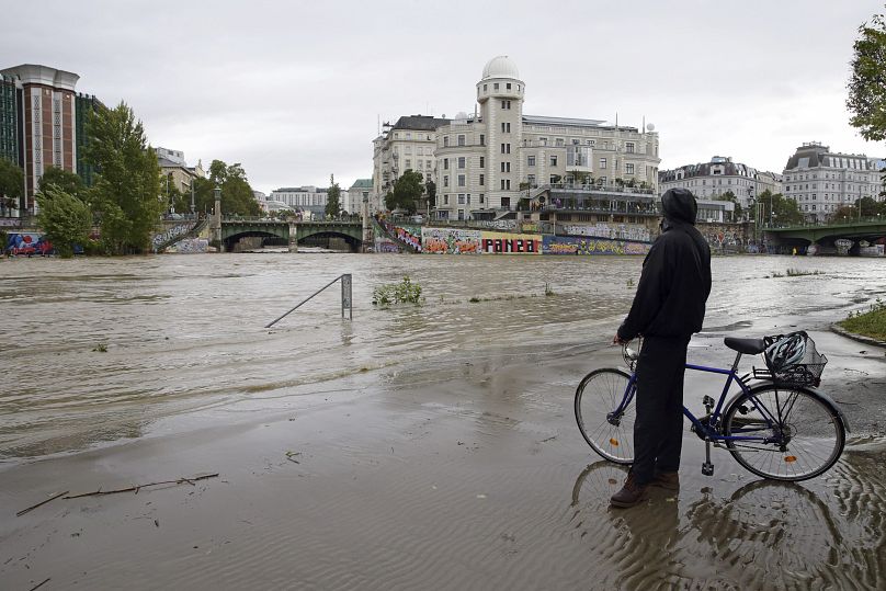 Un cycliste regarde le canal Donaukanal en crue à l'observatoire Urania dans le centre de Vienne, en Autriche, le dimanche 15 septembre 2024.